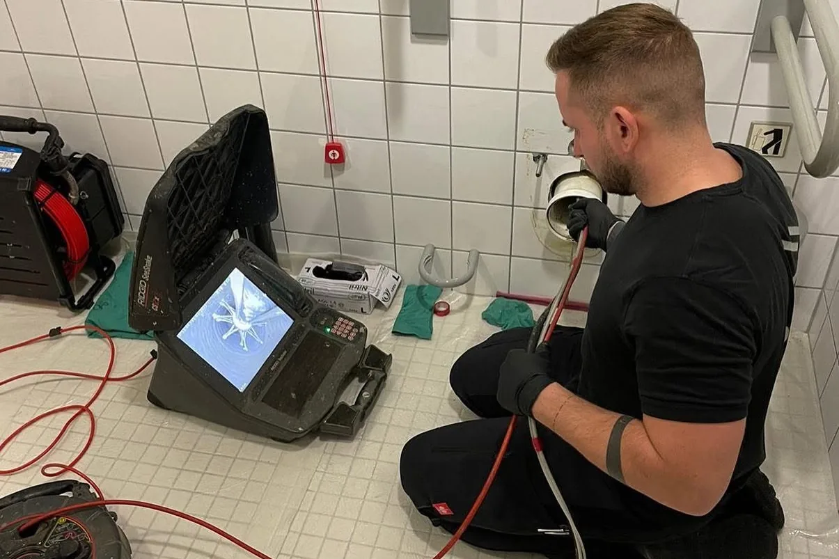 Kamerabefahrung einer Abwasserleitung: Techniker der P&N Kanaltechnik GmbH mit Kanalkamera in einem Sanitärraum